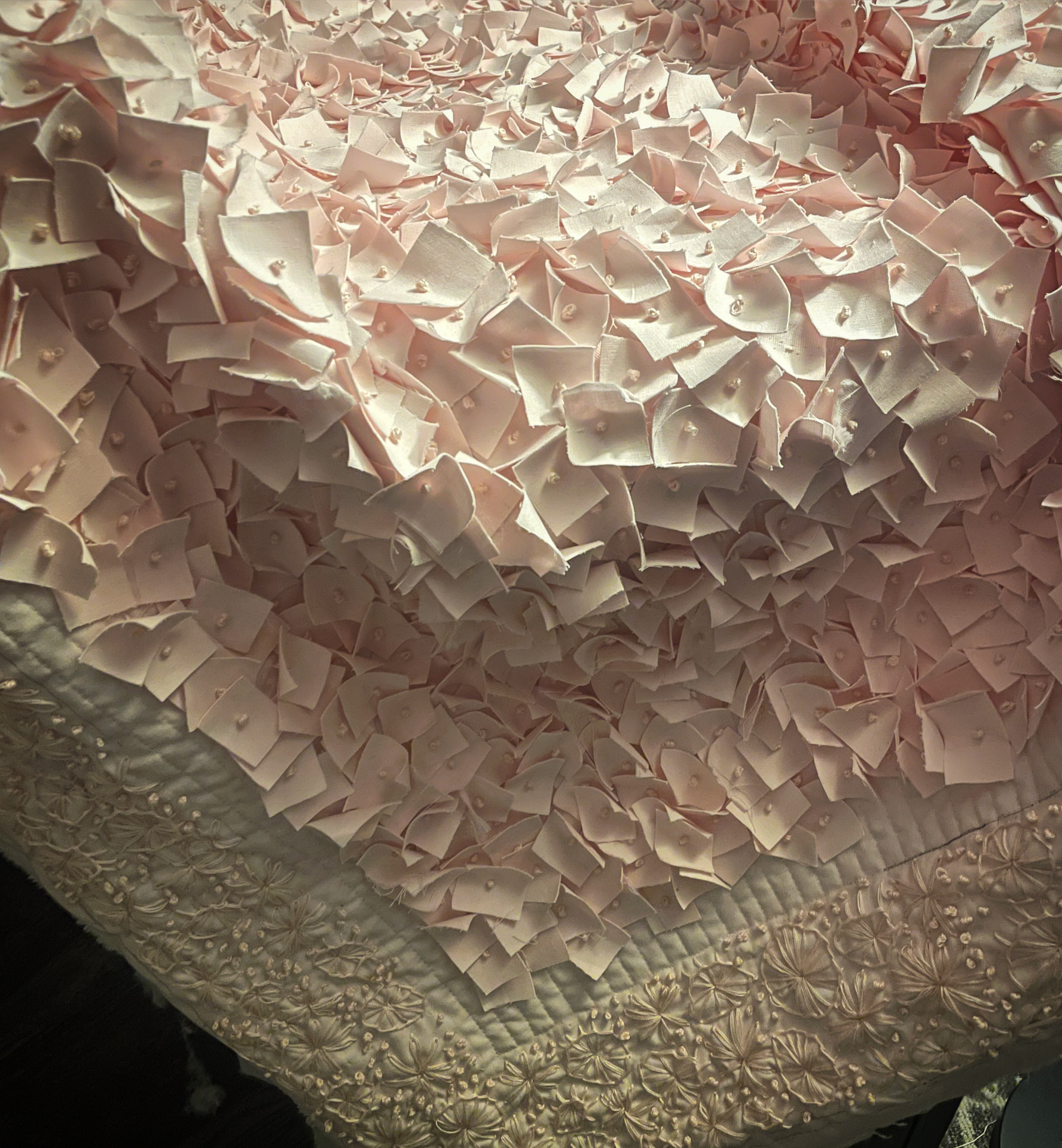 Macro detail of hand quilting in soft pink and blush tones